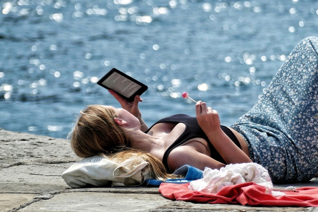 夏日海边美女躺着看电子书图片