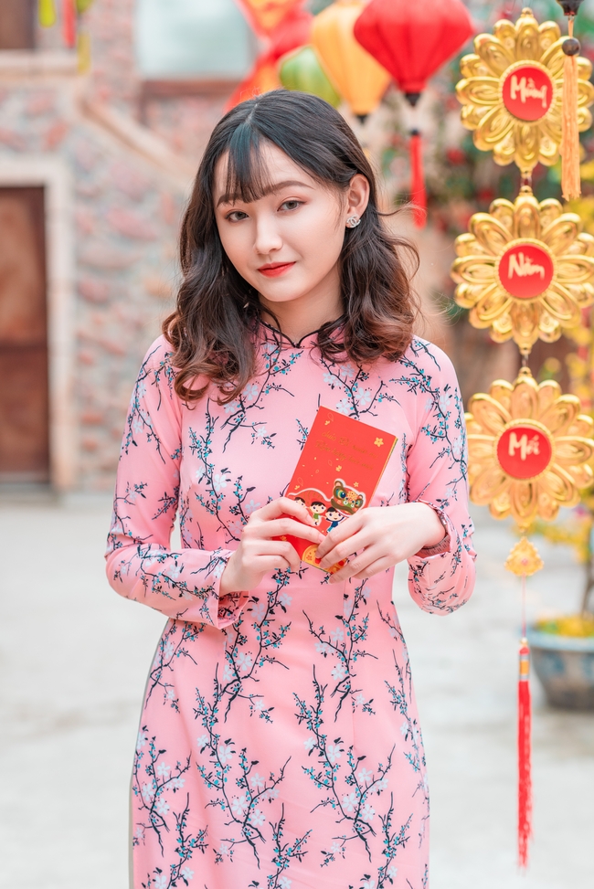 手持红包袋的越南粉色花卉奥黛美女图片