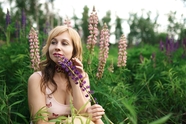 站在花丛手持紫色花枝美女写真图片