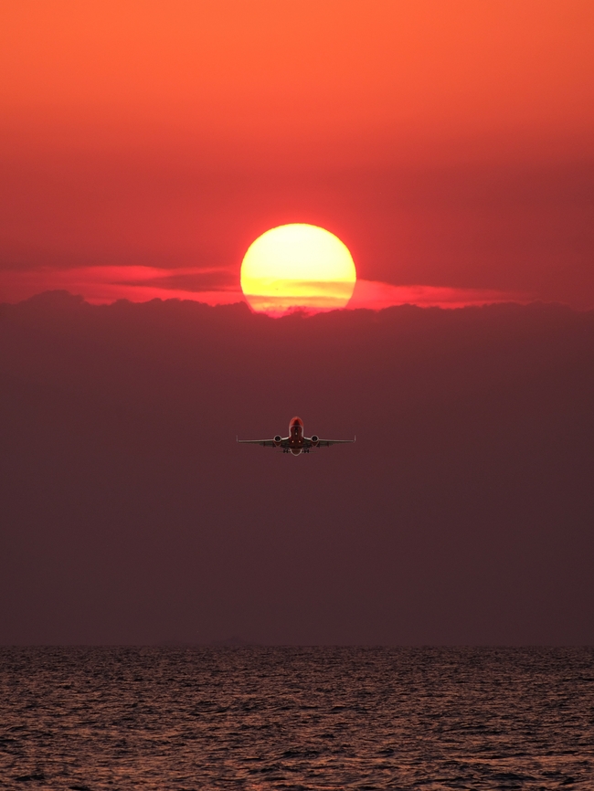 黄昏落日余晖海面飞行的飞机图片