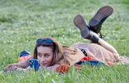 趴在草地上玩手机的美女图片
