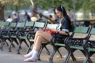 欧美美女坐在公园椅子上玩手机图片