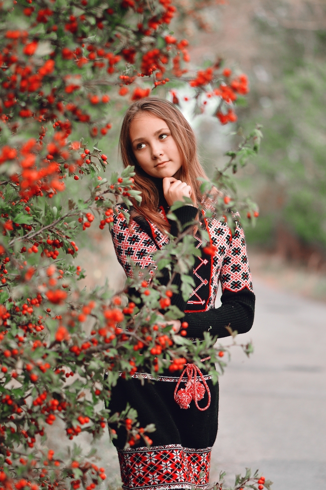 站在红色火棘果树旁边的美女图片