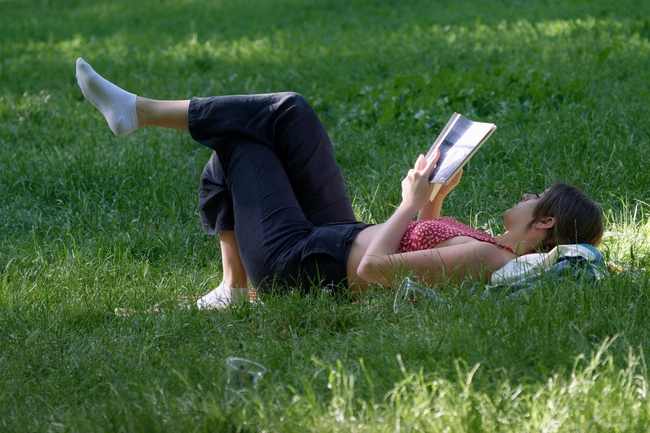 躺在绿色草地上看书的少女图片