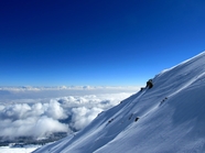 蓝色天空白色云海雪山山坡摄影图片