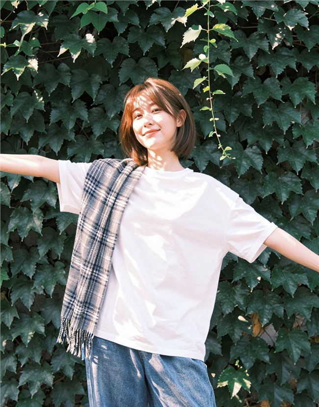 站在绿植墙前的白色T恤美女图片