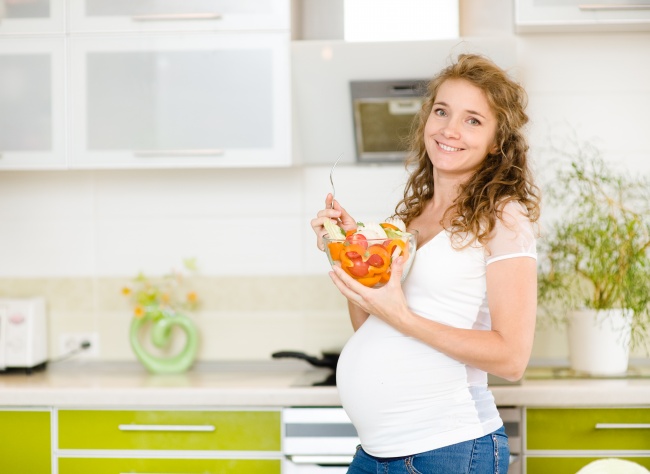 厨房里在吃沙拉的孕妇图片
